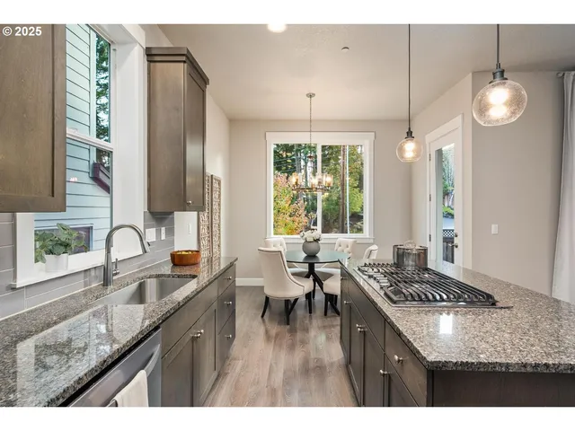 a kitchen with granite countertop a stove a sink a refrigerator dining table and chairs