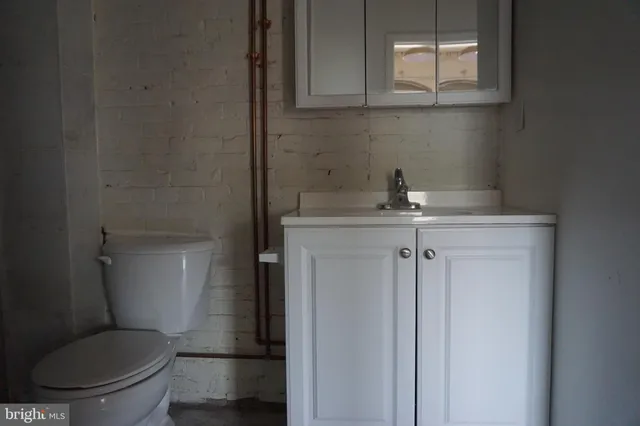 a bathroom with a granite countertop toilet sink and mirror