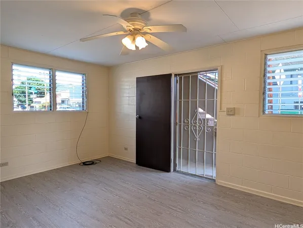 an empty room with windows and fan