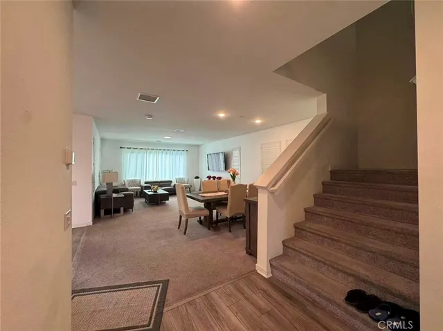 a living room with furniture and a dining table with wooden floor