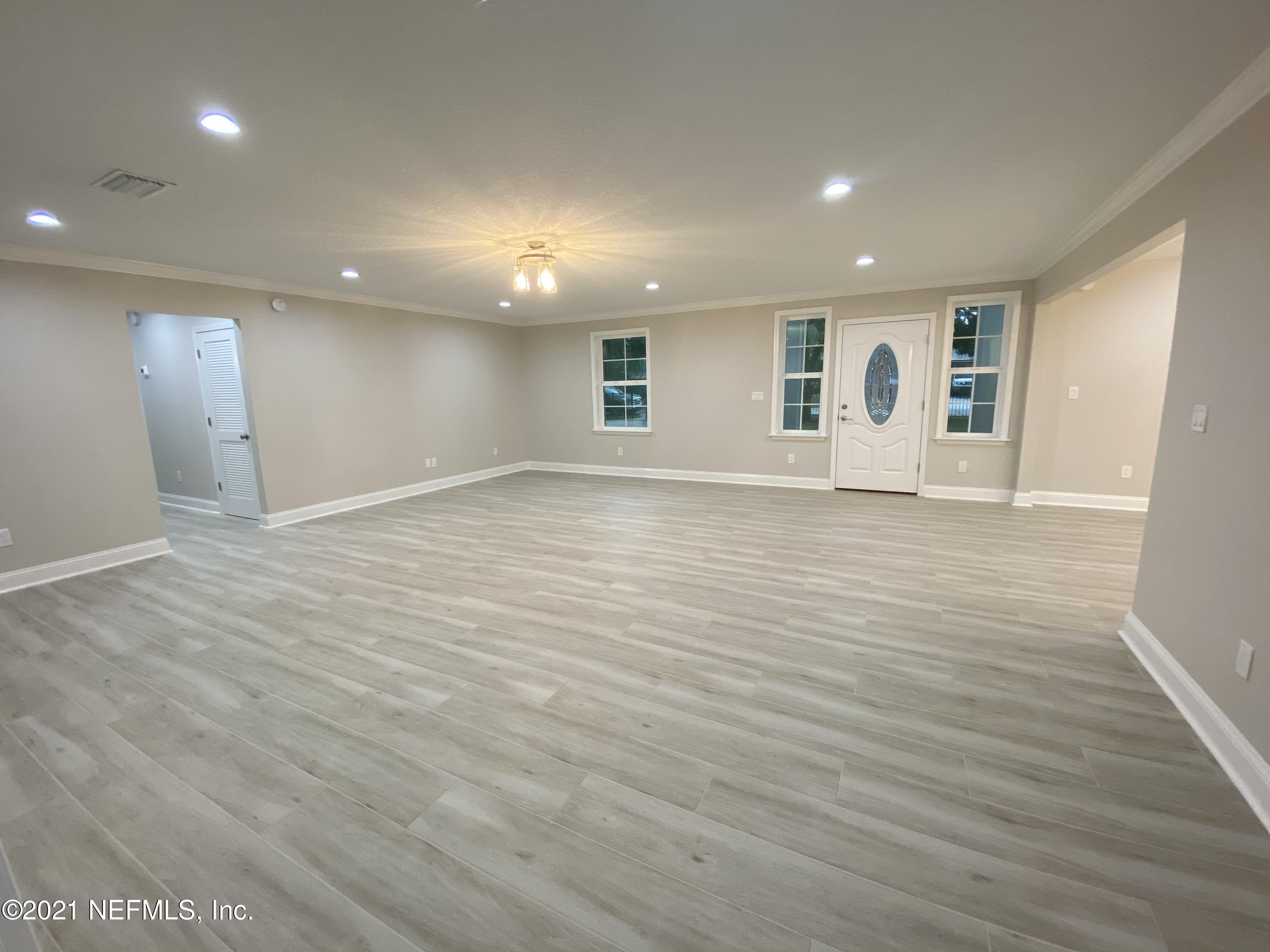 9709 Lily Road Jacksonville, FL 32246 - Photo 5 of 60 an empty room with wooden floor and windows