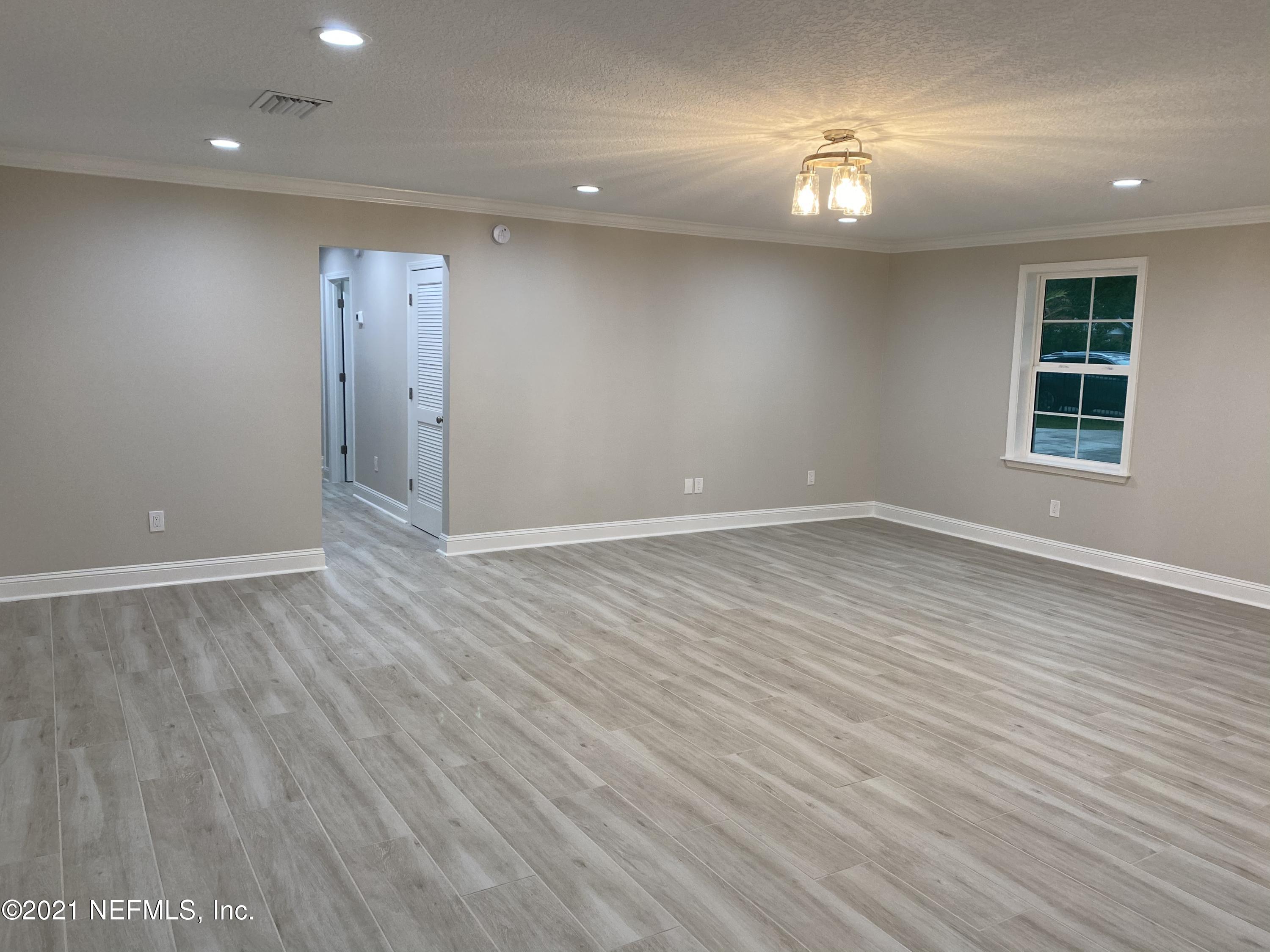 9709 Lily Road Jacksonville, FL 32246 - Photo 7 of 60 an empty room with wooden floor and windows
