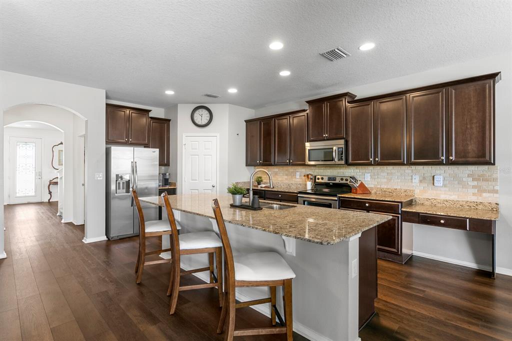 2839 Maple Brook Loop Lutz, FL 33558 - Photo 12 of 61 a kitchen with stainless steel appliances granite countertop wooden cabinets a stove top oven a sink and dishwasher
