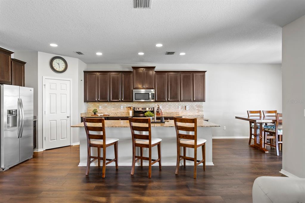 2839 Maple Brook Loop Lutz, FL 33558 - Photo 8 of 61 an open kitchen with wooden floor and stainless steel appliances