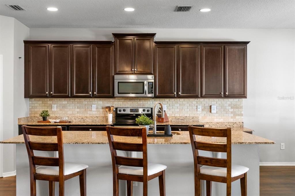 2839 Maple Brook Loop Lutz, FL 33558 - Photo 9 of 61 a kitchen with stainless steel appliances wooden cabinets and a chairs