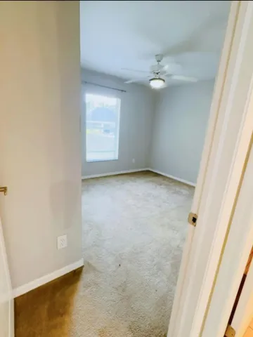 an empty room with a ceiling fan and a window