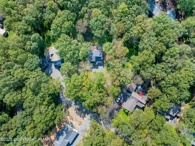 an aerial view of a house with a yard and large trees
