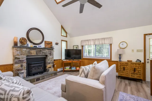 a living room with furniture a fireplace a flat screen tv and a large window