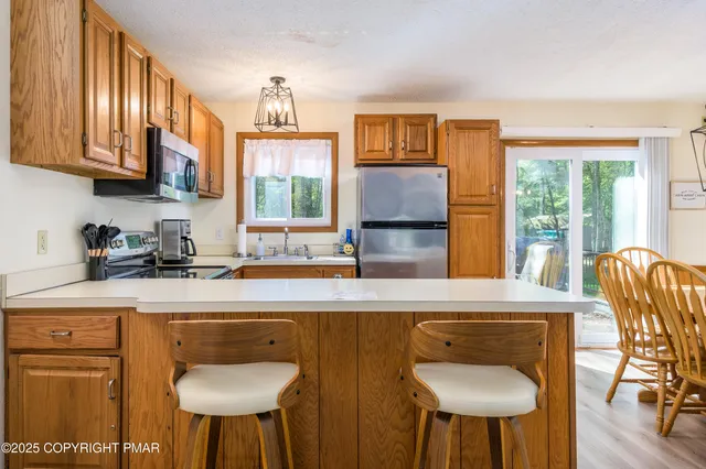 a kitchen with stainless steel appliances granite countertop a sink a stove a dining table and chairs with wooden floor