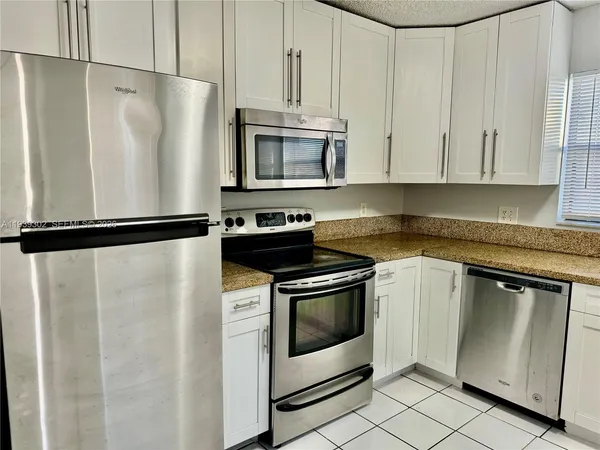 a kitchen with stainless steel appliances granite countertop white cabinets a refrigerator and a stove