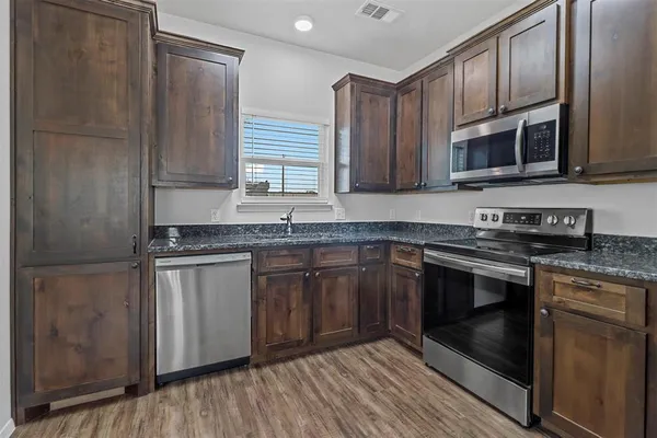 a kitchen with stainless steel appliances granite countertop a stove a sink and a microwave