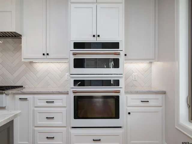a kitchen with granite countertop white cabinets and white stove