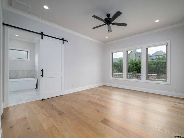 a view of an empty room with a window and a kitchen view