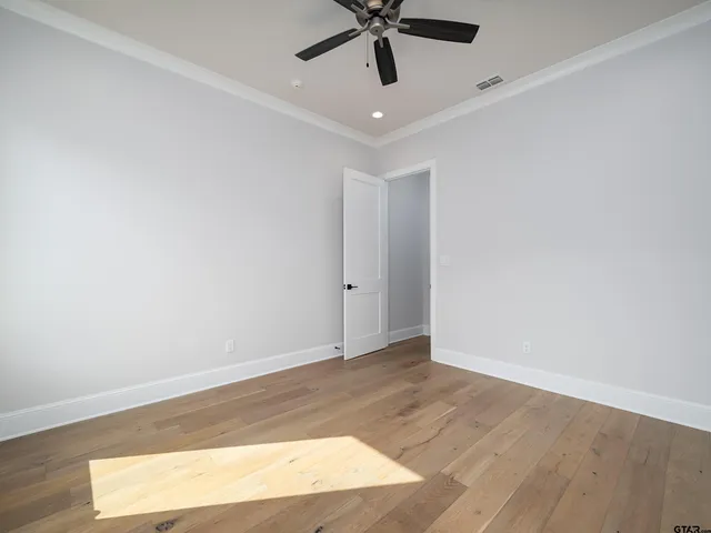 an empty room with wooden floor and ceiling fan