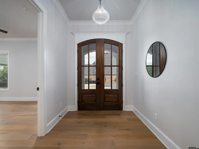 an empty room with wooden floor mirror and windows