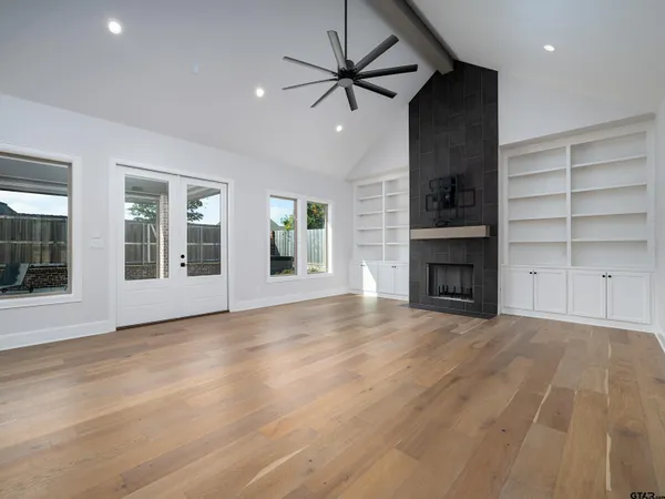 a view of an empty room with a window and a kitchen view