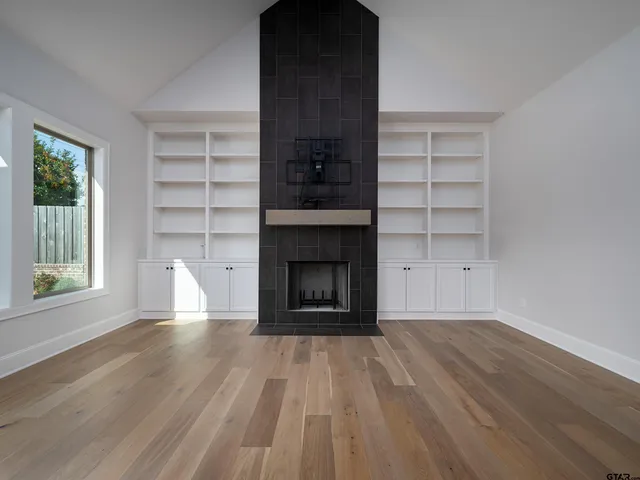 a view of an empty room with a window and fire place