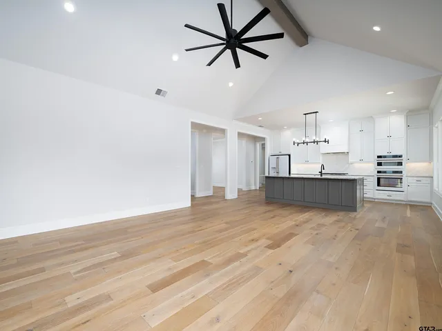 a view of kitchen and empty room with wooden floor