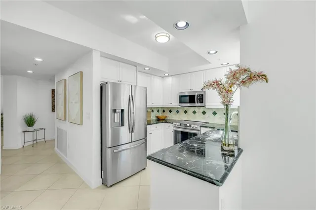 a kitchen that has a refrigerator a stove and white cabinets