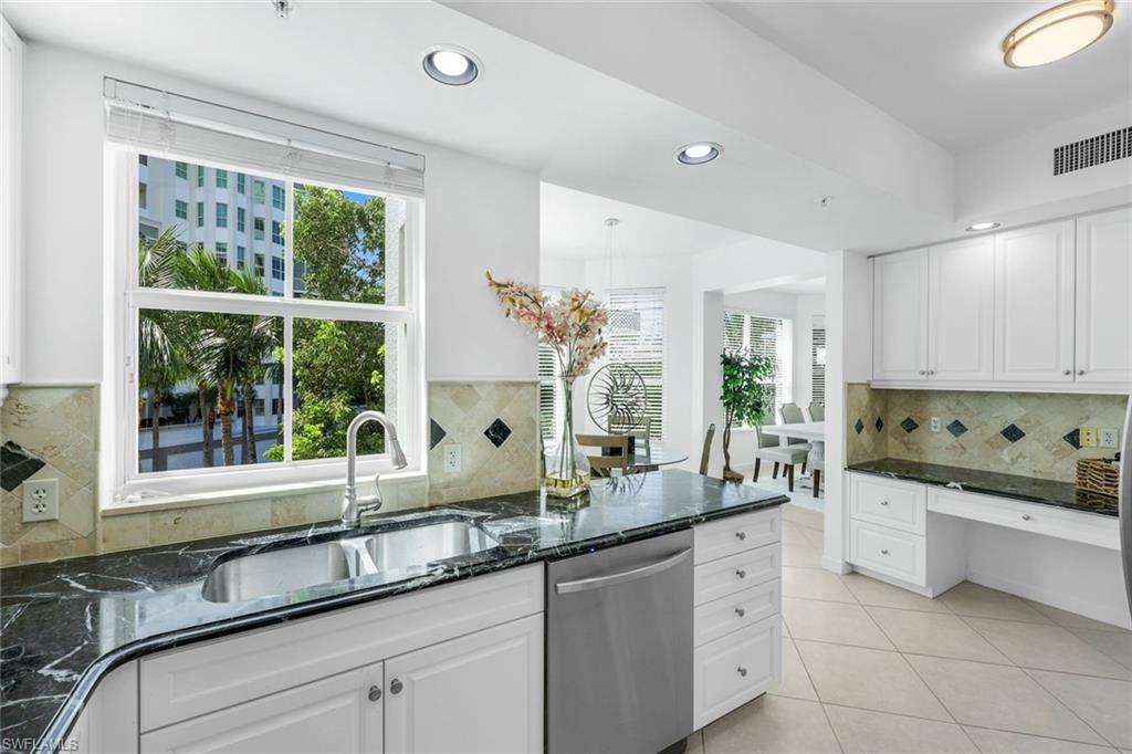 315 Dunes Boulevard, Unit 201 Naples, FL 34110 - Photo 6 of 30 a kitchen with granite countertop a sink and white cabinets