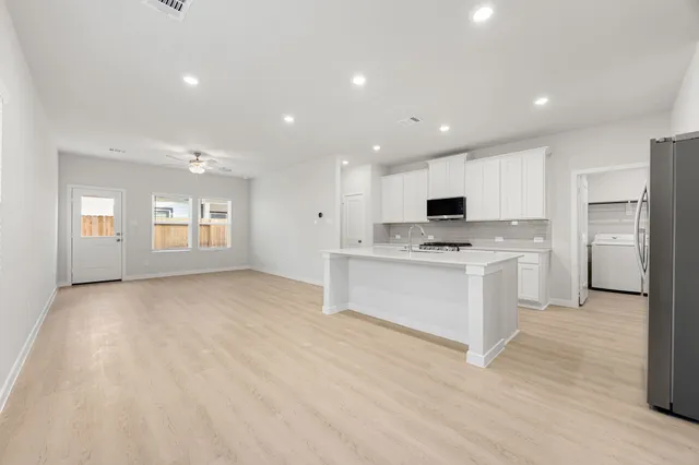 a view of kitchen with stainless steel appliances refrigerator oven microwave and cabinets