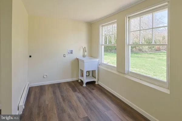 an empty room with wooden floor a window and a large window