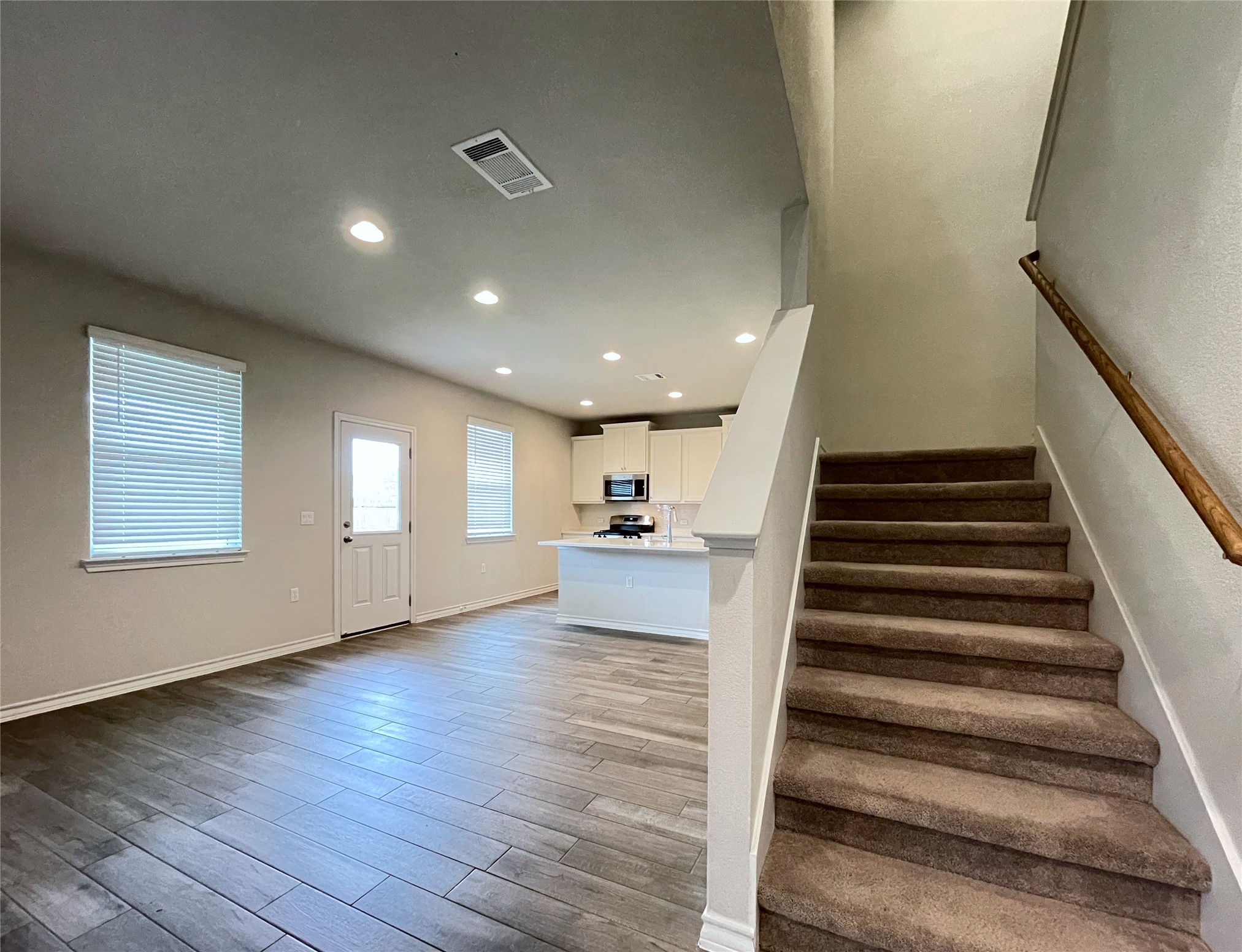 1602 Jacey Way Austin, TX 78725 - Photo 14 of 33 Open-concept living space featuring wood-finish flooring, recessed lighting, and multiple windows with blinds