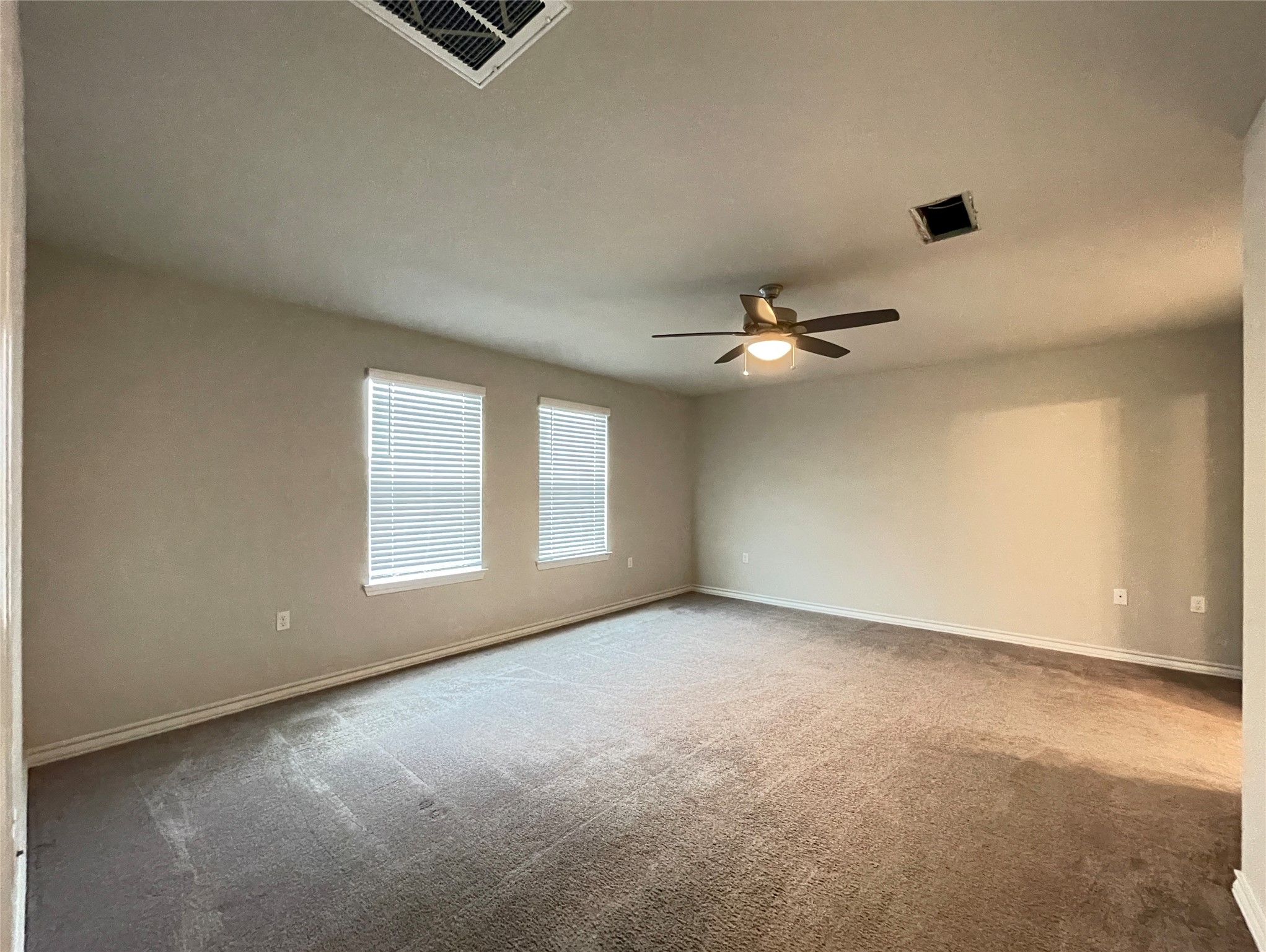1602 Jacey Way Austin, TX 78725 - Photo 22 of 33 Carpeted interior space featuring two windows with horizontal blinds, a ceiling fan with integrated lighting, and a ceiling vent