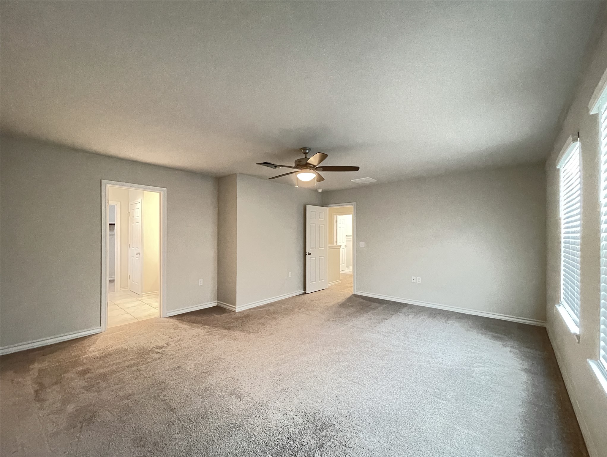 1602 Jacey Way Austin, TX 78725 - Photo 23 of 33 Spacious room featuring neutral carpeting, light-toned walls, and multiple windows with blinds