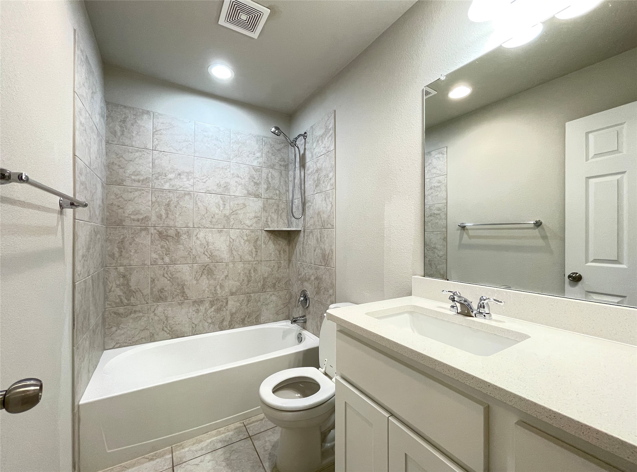1602 Jacey Way Austin, TX 78725 - Photo 29 of 33 Bathroom featuring a tub/shower combination with tiled surround, a built-in shower shelf, a vanity with an integrated sink and light-colored countertop, and a wall-mounted mirror