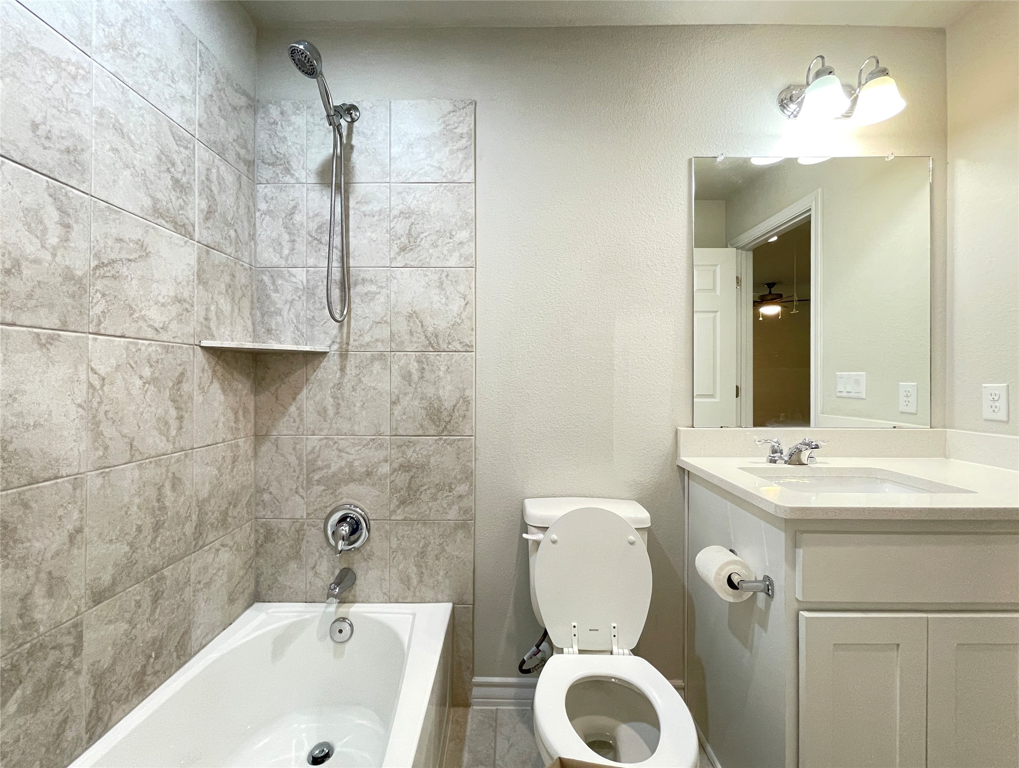 1602 Jacey Way Austin, TX 78725 - Photo 30 of 33 Bathroom featuring a white bathtub, gray tiled shower surround with built-in shelf, chrome fixtures, and a vanity with white cabinetry and a light-toned countertop