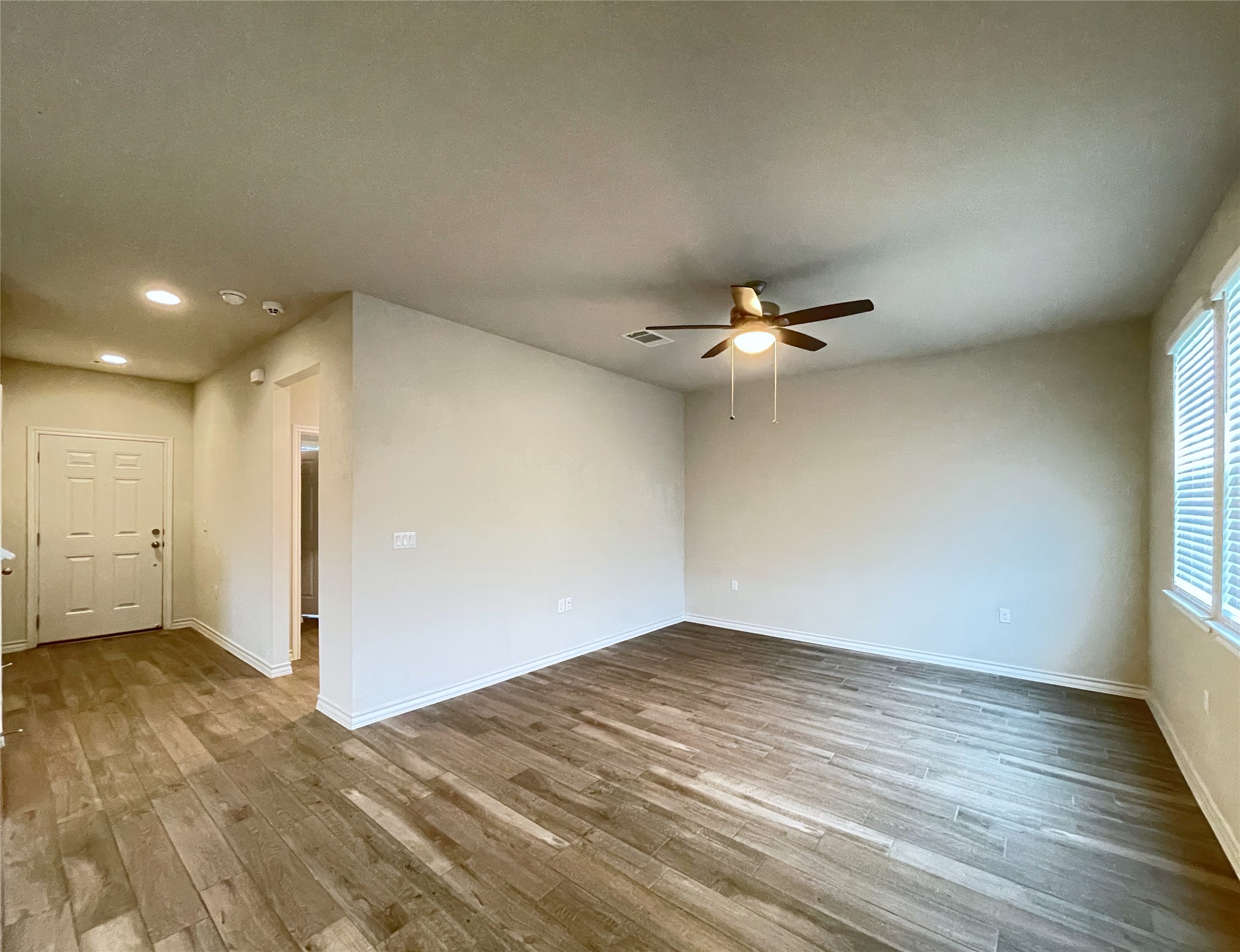 1602 Jacey Way Austin, TX 78725 - Photo 3 of 33 Spacious interior room featuring wood-look tile flooring, neutral wall tones, and a ceiling fan with integrated lighting