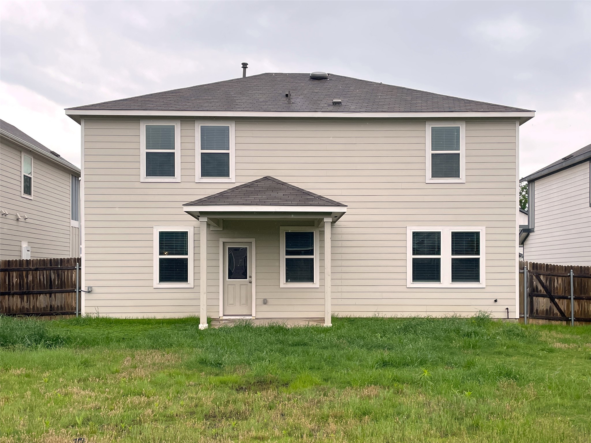 1602 Jacey Way Austin, TX 78725 - Photo 32 of 33 Two-story residential structure featuring a covered patio, multiple windows, light-toned siding, and a dark shingle roof