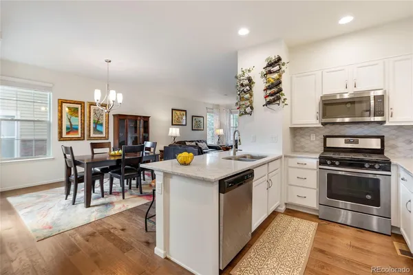 a kitchen that has a lot of white cabinets and stainless steel appliances