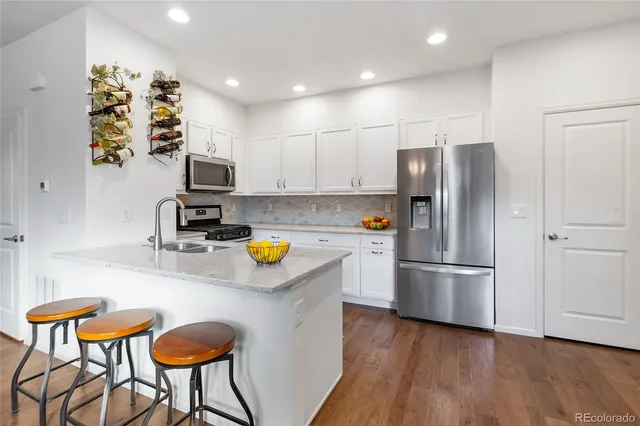 a kitchen with stainless steel appliances a refrigerator a stove a sink cabinets and a dining table with chairs