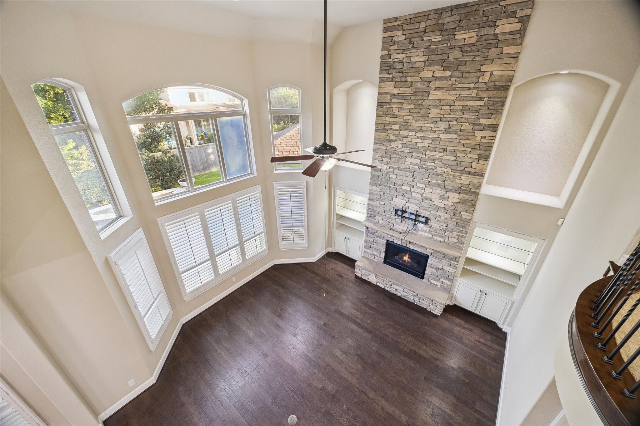 35 North Fremont Ridge Loop Spring, TX 77389 - Photo 19 of 37 A breathtaking perspective from the upper-level iron-railed balcony reveals the grandeur of the family room, where soaring ceilings, a striking floor-to-ceiling stone fireplace, and expansive windows create a bright and inviting atmosphere.