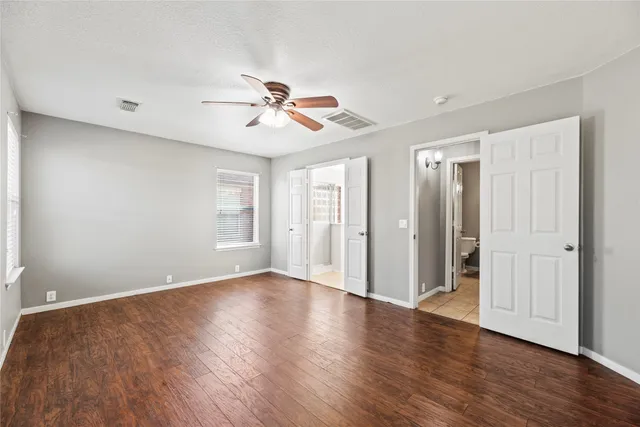 a view of empty room with wooden floor and fan