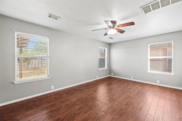 a view of an empty room with wooden floor and a window