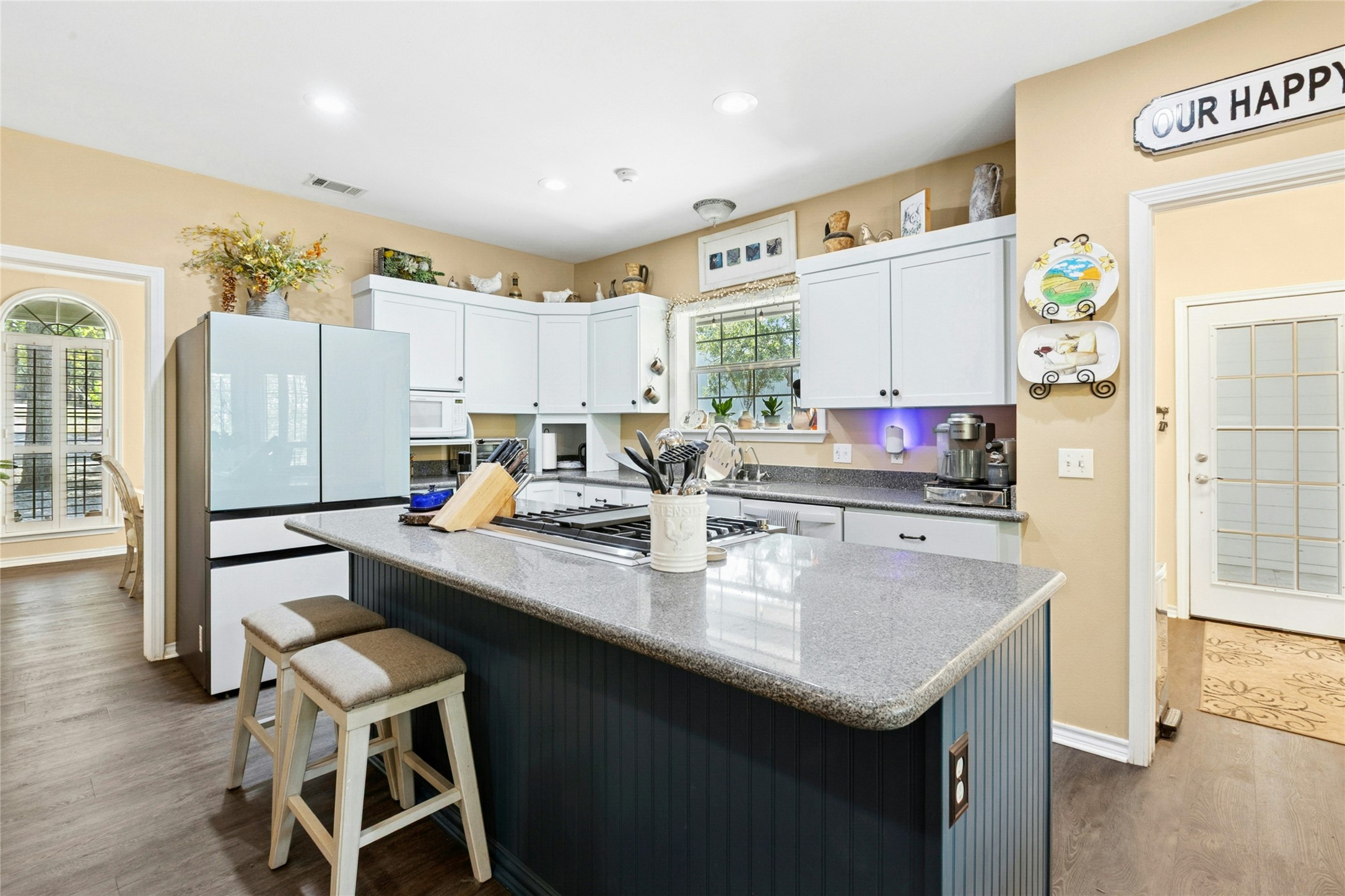 412 Woody Hollow Road Luling, TX 78648 - Photo 10 of 33 Kitchen with a breakfast bar, white cabinetry, dark wood-type flooring, freestanding refrigerator, and a kitchen island