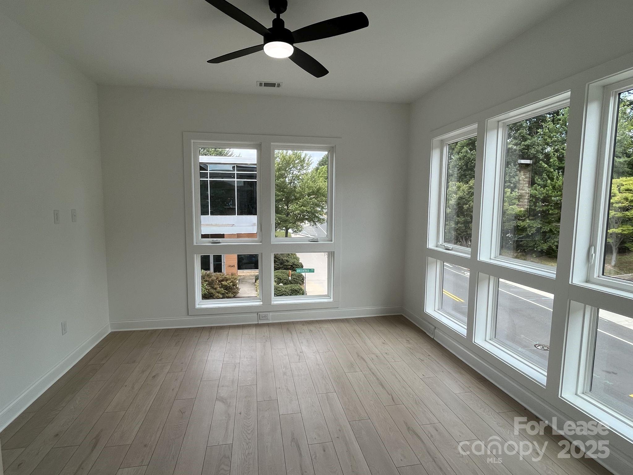 19546 Greentree Way, Unit 201 Cornelius, NC 28031 - Photo 18 of 31 an empty room with wooden floor fan and windows
