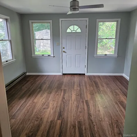 a view of an empty room with wooden floor and a window