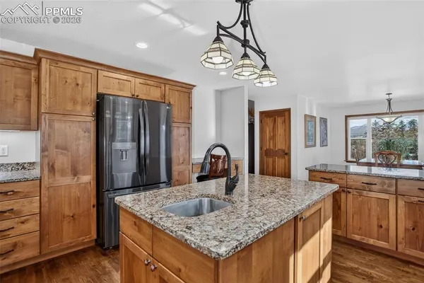 a kitchen with kitchen island granite countertop a sink and refrigerator