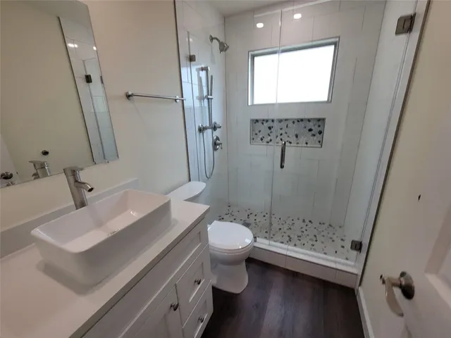 a bathroom with a sink a toilet a mirror and shower