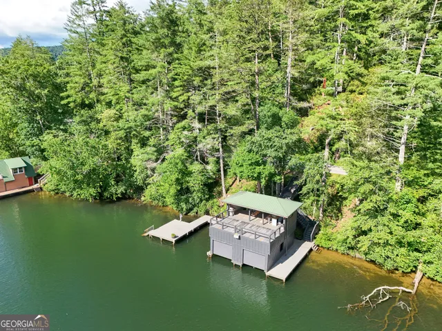 a swimming pool with outdoor seating and trees in the background