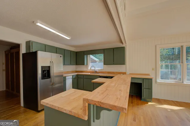 a kitchen with stainless steel appliances granite countertop a refrigerator a stove and a sink