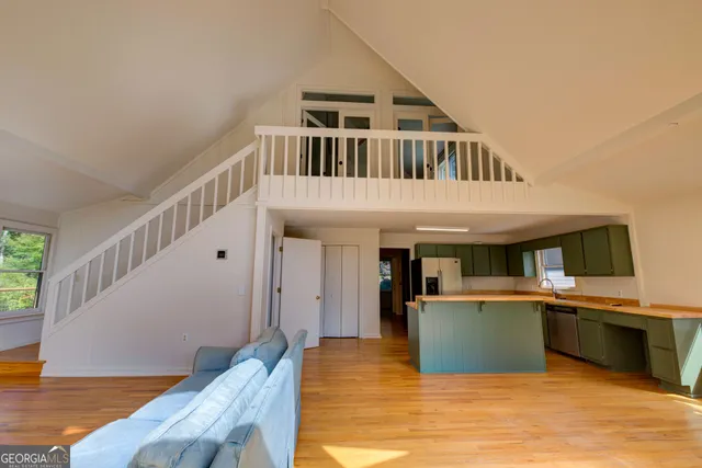 a view of a kitchen with kitchen island a sink wooden floor and a living room