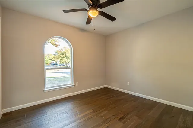 an empty room with wooden floor chandelier and windows