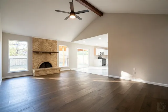 a view of empty room with wooden floor and fireplace