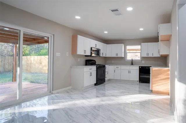 a kitchen with granite countertop a stove a sink and a refrigerator