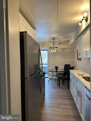 a kitchen with stainless steel appliances granite countertop a refrigerator a stove and a dining table with wooden floor